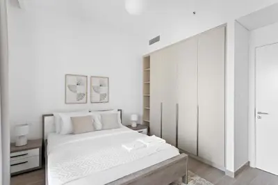 a white bedroom with a large bed with white walls at Silkhaus Stylish 1BDR with Pool & Balcony Dubai Creek Harbour in Dubai