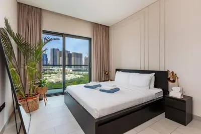 a bedroom with a bed and a large window at 1B with Park and Burj Khalifa View, Hartland Waves in Dubai