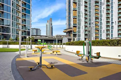 a park with tables and benches and tall buildings at 1B with Park and Burj Khalifa View, Hartland Waves in Dubai