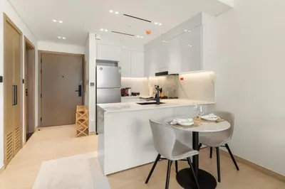 a white kitchen with a small table and chairs at Elegant 1BR Living at Binghatti Emerald in Dubai
