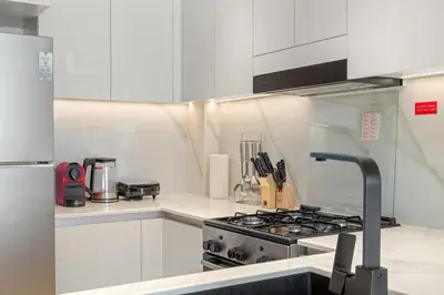 a kitchen with white cabinets and a stove top oven at Elegant 1BR Living at Binghatti Emerald in Dubai