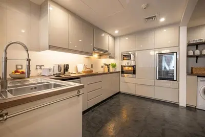 a large white kitchen with a sink and a dishwasher at Trident Grand! Near Beach, Pool and Gym Access! In JBR-Dubai Marina in Dubai