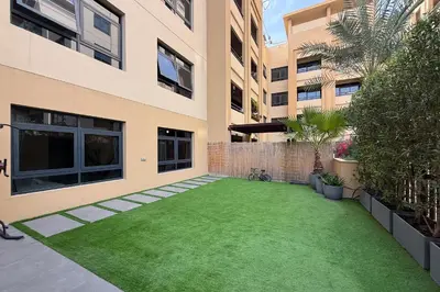 a backyard with a green lawn in front of a building at Spacious 3BR with Large Terrace in Dubai