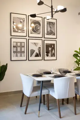 a dining room table with white chairs and pictures on the wall at Spacious 3BR with Large Terrace in Dubai
