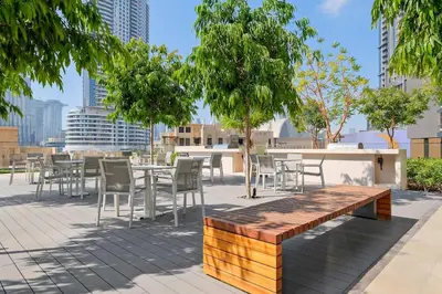 a wooden bench and tables and chairs on a patio at Silkhaus Luxurious 1BR with Balcony Pool and Gym Downtown in Dubai