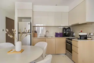 a kitchen with a table and a refrigerator at Silkhaus Luxurious 1BR with Balcony Pool and Gym Downtown in Dubai