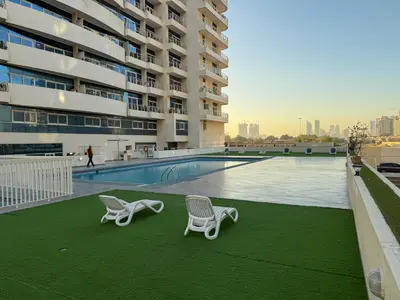 two chairs and a swimming pool on the roof of a building at 902, Royal Residencies, Dubai Sports City in Dubai