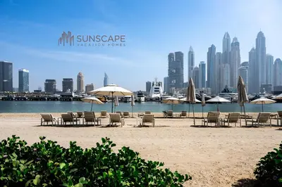 a beach with chairs and umbrellas in front of a city at Beachfront 1BR with Private Beach Access and Balcony in Dubai