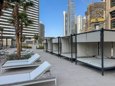 a rooftop patio with benches and palm trees in a city at Modern 2Bed with Iconic Burj Khalifa & Canal Views in Dubai