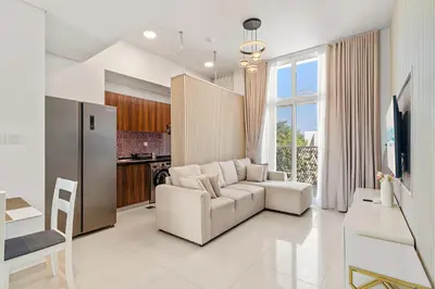 a living room with a white couch and a kitchen at Stylish Community 2BR Avencia 2,DAMAC Hills-2 in Dubai