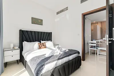 a bedroom with a black and white bed and a table at Stylish Community 2BR Avencia 2,DAMAC Hills-2 in Dubai