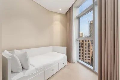 a white bed in a room with a large window at Westminster Imperial Avenue Downtown in Dubai