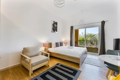 a bedroom with a bed and a chair and a window at Chic Studio Near Circle Mall & Dubai Sports City in Dubai