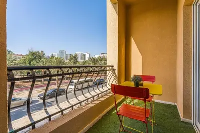 a balcony with two chairs and a view of a highway at Chic Studio Near Circle Mall & Dubai Sports City in Dubai