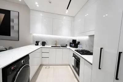 a white kitchen with white cabinets and a stove at Refined Luxury 1BR Binghatti Azure in Dubai