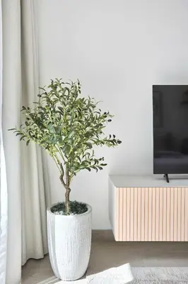 a plant in a white vase in a living room at Frank Porter - Luma 21 in Dubai