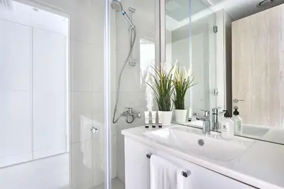 a white bathroom with a sink and a shower at Frank Porter - Luma 21 in Dubai