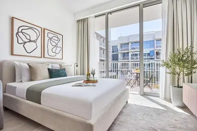 a white bedroom with a large bed and a balcony at Frank Porter - Luma 21 in Dubai