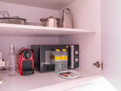 a kitchen shelf with bottles of water and a microwave at StudioOne Tower Sky-High Marina Chic, Sea Views & Designer Pool in Dubai