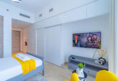 a bedroom with a bed with a tv on the wall at StudioOne Tower Sky-High Marina Chic, Sea Views & Designer Pool in Dubai