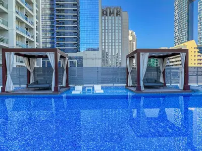 a swimming pool with two chairs in a city at StudioOne Tower Sky-High Marina Chic, Sea Views & Designer Pool in Dubai