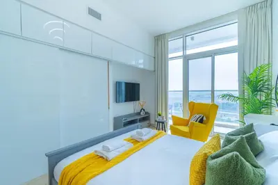 a bedroom with a large bed and a yellow chair at StudioOne Tower Sky-High Marina Chic, Sea Views & Designer Pool in Dubai