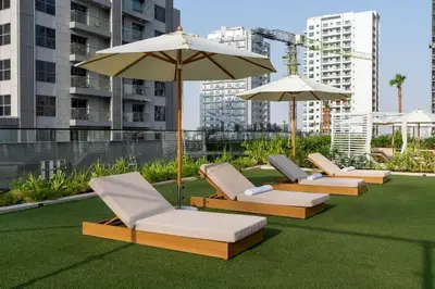 a row of lounge chairs and an umbrella on a lawn at Chic 1BR Urban Retreat Binghatti Phantom in Dubai