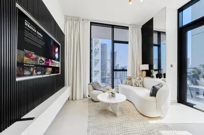 a living room with white furniture and large windows at Elegant 2BR Apartment with Private Pool in JVC in Dubai