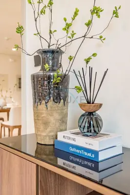 a table with books and a vase on top at Prime Waterfront Living with Partial Sea Views, Just a Short Drive from Palm Jumeirah, Marina Vista Tower 1, Emaar Beachfront by Deluxe Holiday Homes in Dubai