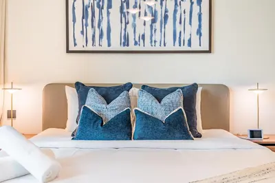 a bedroom with a bed with blue and white pillows at Prime Waterfront Living with Partial Sea Views, Just a Short Drive from Palm Jumeirah, Marina Vista Tower 1, Emaar Beachfront by Deluxe Holiday Homes in Dubai