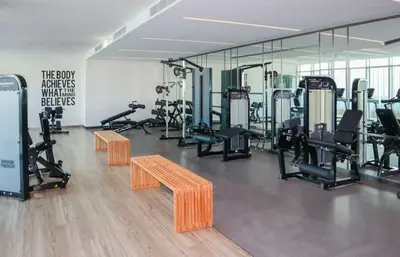a gym with tread machines and a bench and mirrors at Prime Waterfront Living with Partial Sea Views, Just a Short Drive from Palm Jumeirah, Marina Vista Tower 1, Emaar Beachfront by Deluxe Holiday Homes in Dubai