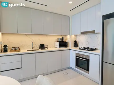 a white kitchen with white cabinets and appliances at HiGuests - Beautiful Sea Facing 1BR at Emaar Beachfront in Dubai
