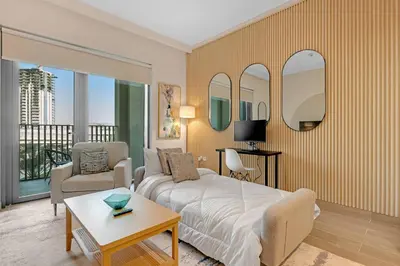 a bedroom with a bed and a living room with a balcony at Stylish Chic 1BR with Lagoons Access - Creek Beach in Dubai