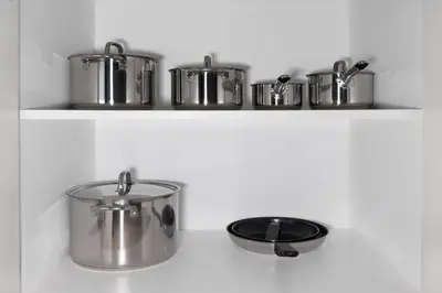 a row of pots and pans on a shelf at Penthouse Vibes 3BR Billiard & Air Hockey in Dubai