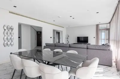 a dining room with a glass table and white chairs at Penthouse Vibes 3BR Billiard & Air Hockey in Dubai