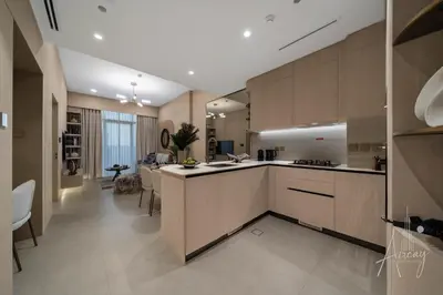 a kitchen with wooden cabinets and a living room at Sweet Escape 1BR in JVC Near Circle Mall in Dubai