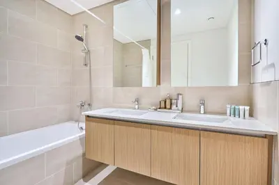 a bathroom with a sink and a tub and a mirror at Modern 2BR Apartment at Grove 5 - Creek Beach & Pool Access in Dubai