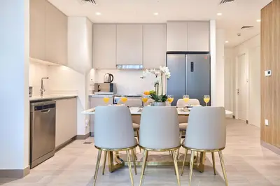 a kitchen and dining room with a table and chairs at Modern 2BR Apartment at Grove 5 - Creek Beach & Pool Access in Dubai