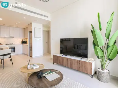 a living room with a coffee table and a kitchen at HiGuests - Sunlit 1 BR Escape with Emaar Beachfront Access in Dubai
