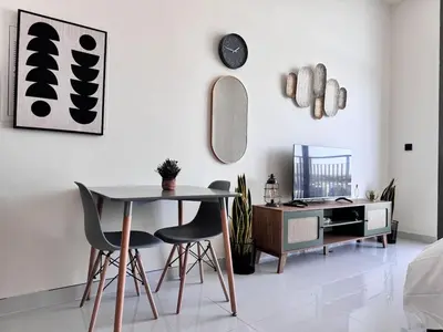 a dining room with a table and chairs and a desk at Pool view Studio with balcony in Arjan in Dubai