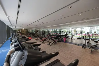 a gym with a row of treadmills and people exercising in it at Pool view Studio with balcony in Arjan in Dubai