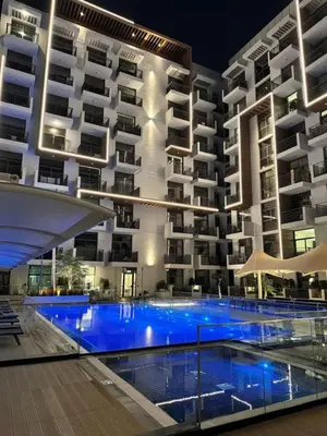 a hotel with a swimming pool in front of a building at Pool view Studio with balcony in Arjan in Dubai