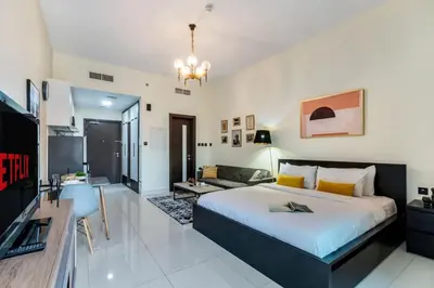 a bedroom with a large bed and a living room at Classy Studio ideal for long stays with balcony in Dubai