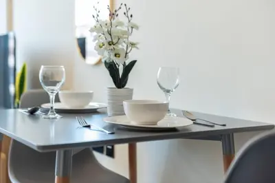 a table with plates and glasses and a vase of flowers at Modern Studio in Barsha south with balcony in Dubai