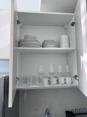 a kitchen shelf with plates and glasses on it at Skyz by Danube Studio Apartment in Arjan , Pool, Gym & Near Miracle Garden in Dubai