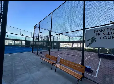 a tennis court with a bench on a tennis court at Skyz by Danube Studio Apartment in Arjan , Pool, Gym & Near Miracle Garden in Dubai