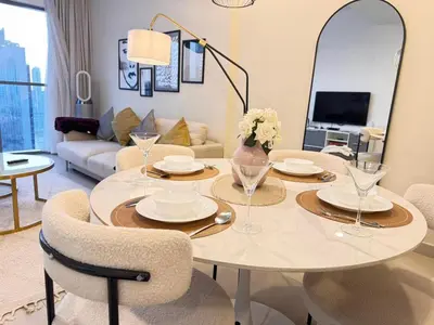a living room with a table with chairs and a couch at Downtown Luxury 1BR with Pool, Gym, Fast WiFi and 8 Min Walk to Burj Khalifa in Dubai