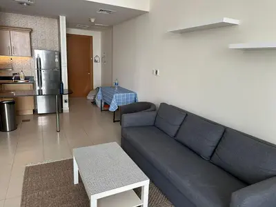 a living room with a couch and a kitchen at Large 1-bedroom by the canal, close to downtown in Dubai