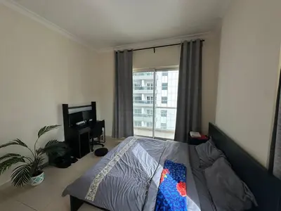 a bedroom with a bed and a tv and a window at Large 1-bedroom by the canal, close to downtown in Dubai