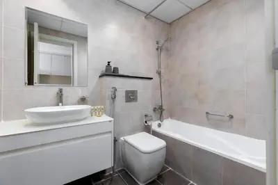 a bathroom with a sink toilet and a mirror at Maison Privee - Refined Studio with Top Facilities in Damac Hills in Dubai